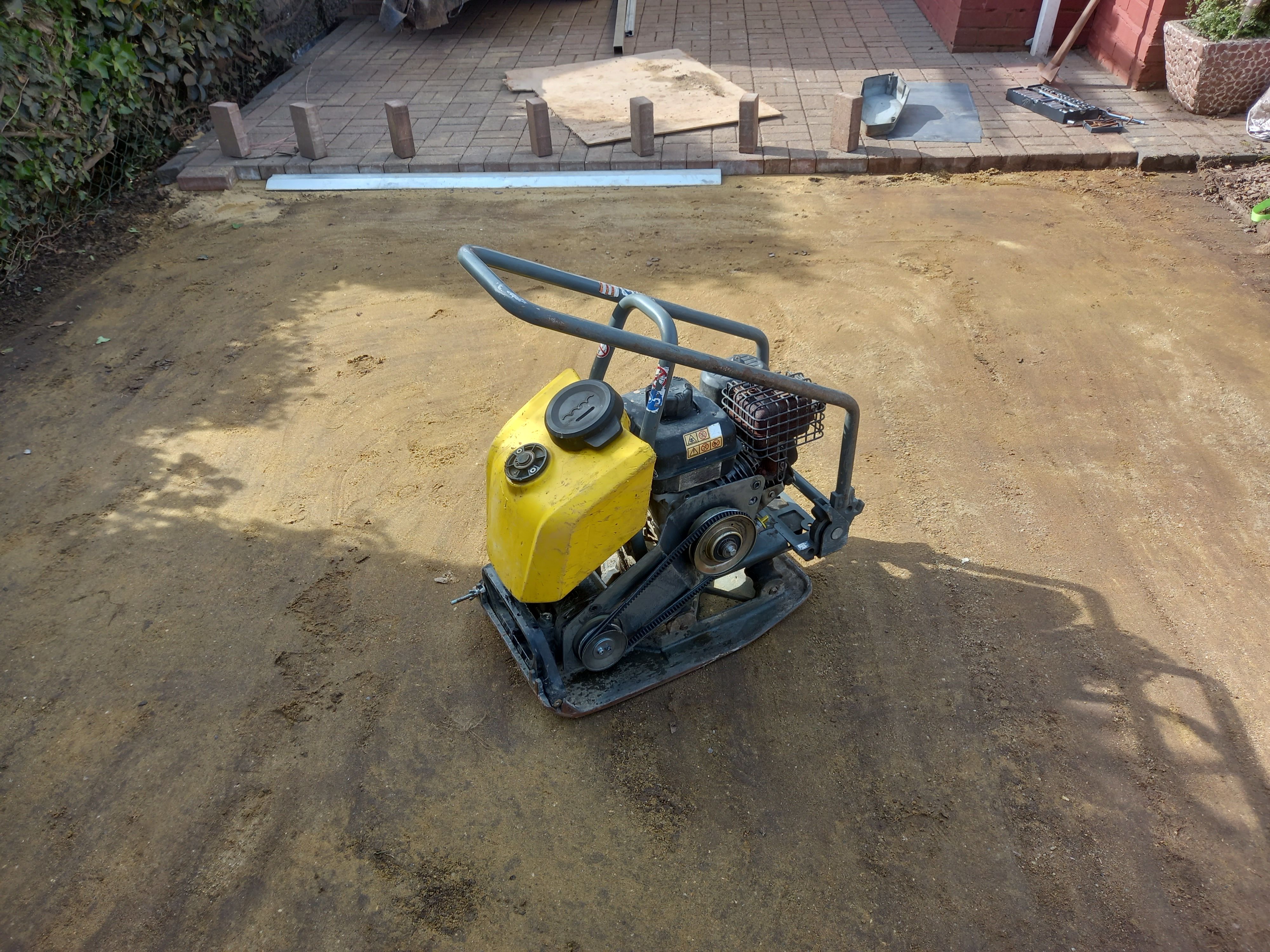 A plate compactor sitting on compacted sand